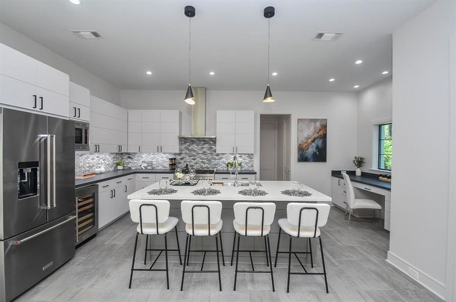 Bright and sparkling, your very workable chef's kitchen provides for easily navigated paths. Storage and organization is prime; with simple white cabinetry (up and down); extended quartz island counter for some stools; muted tile backsplash and shining Kitchen Aid stainless steel appliances.