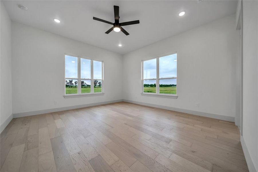 Empty room featuring light hardwood / wood-style floors, a wealth of natural light, and ceiling fan