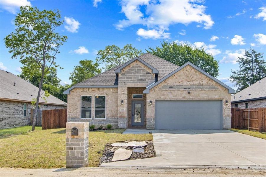 View of front facade featuring a front yard and a garage