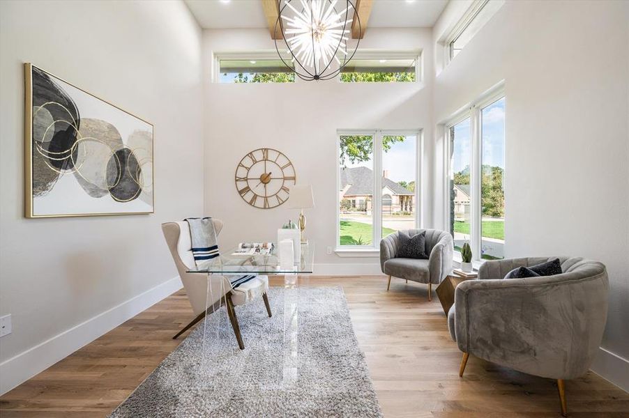 Sitting room with a high ceiling, wood-type flooring, and a chandelier