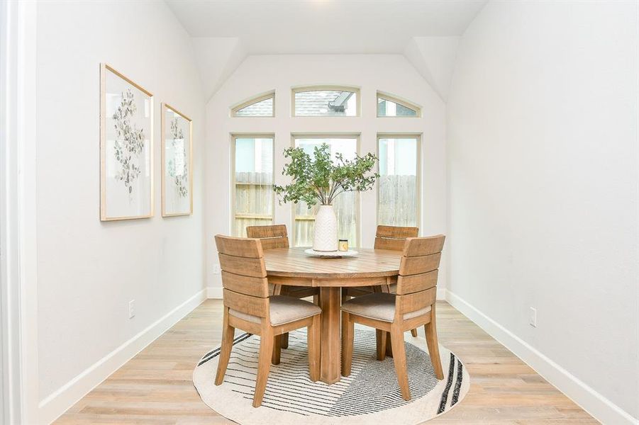 Bright and airy dining nook featuring a high vaulted ceiling with large window.