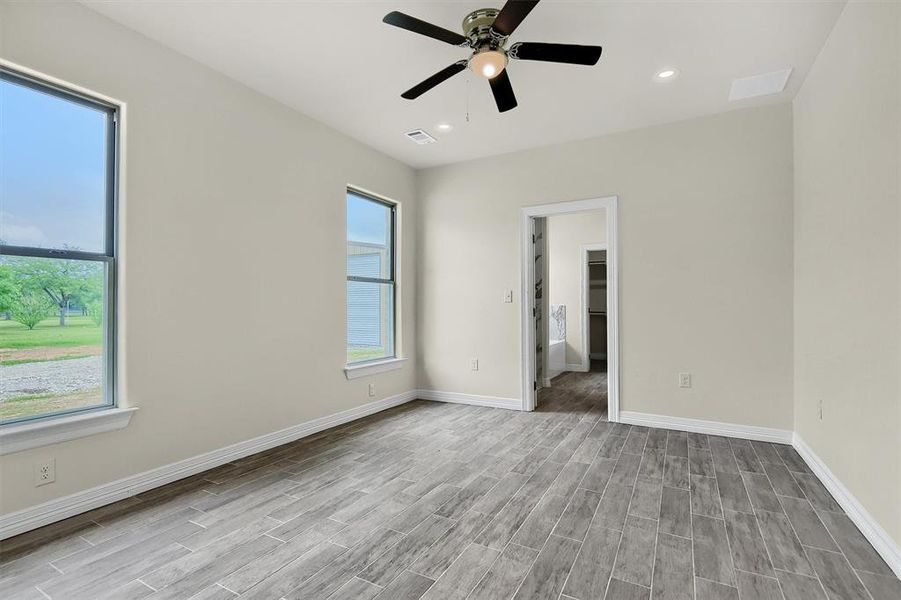 Primary Masteroom with light Tile Plank flooring, and ceiling fan