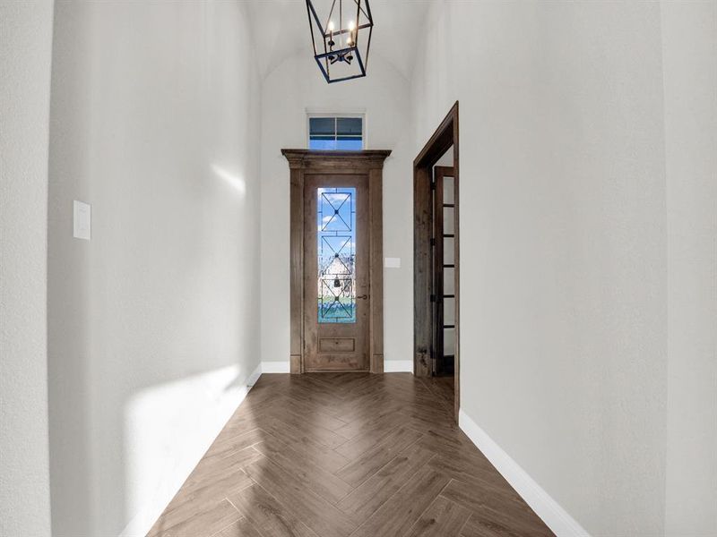 Entrance foyer featuring a towering ceiling, an inviting chandelier, and parquet floors