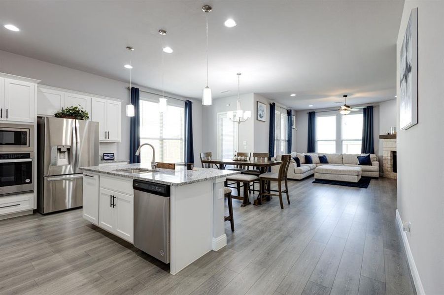 Kitchen with ceiling fan with notable chandelier, a kitchen island with sink, appliances with stainless steel finishes, and white cabinets