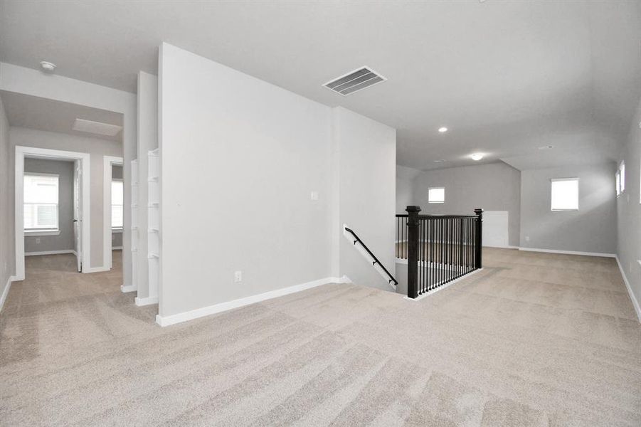 Come upstairs and relish a day of relaxation in this loft area! Ideal as an additional living space or game room, it boasts plush carpeting, high ceilings, custom paint, and windows that flood the area with abundant natural light. Sample photo of completed home with similar floor plan. Actual colors and selections may vary.