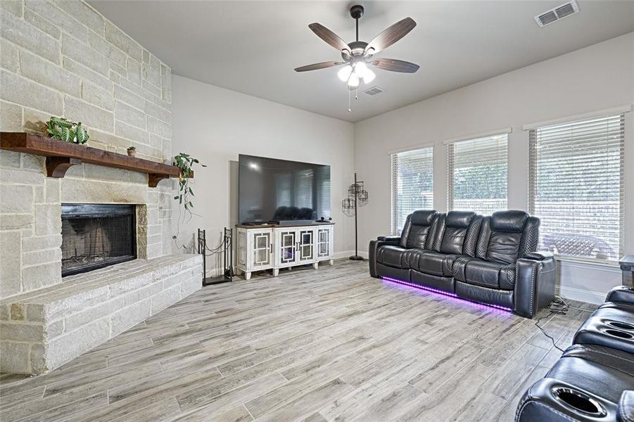 Living room featuring a fireplace, light wood-type flooring, and ceiling fan