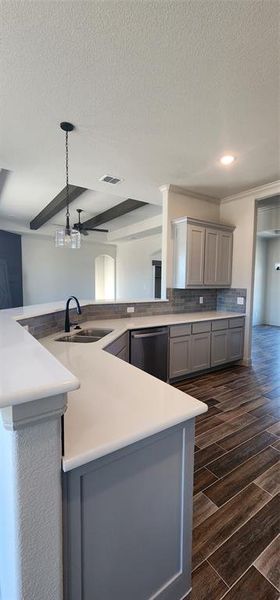 Kitchen with bartop peninsula, decorative light fixtures, sink, backsplash, and dark wood-type flooring