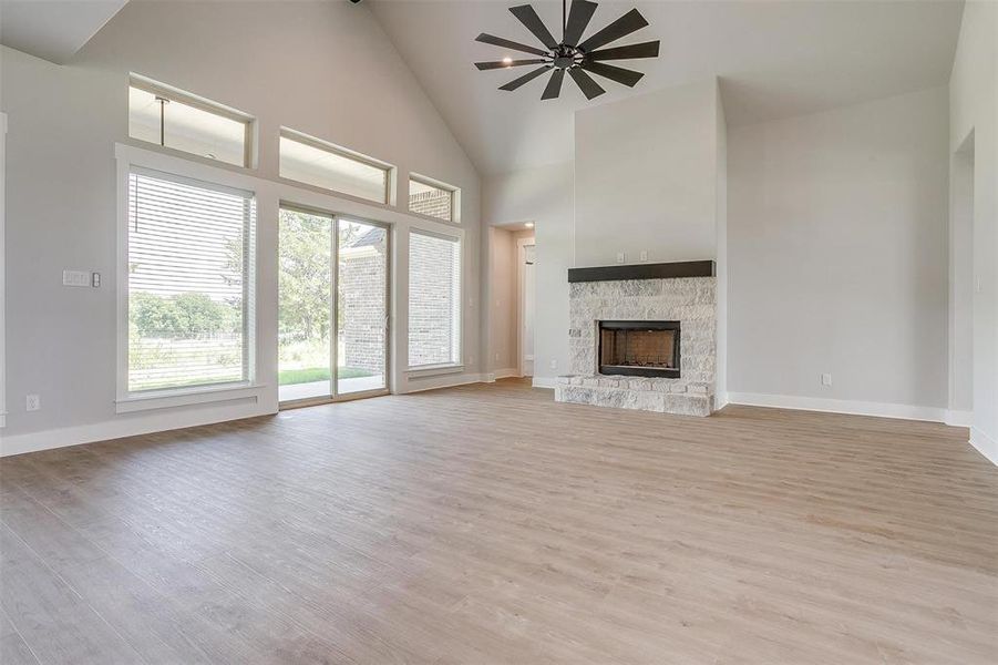 Unfurnished living room featuring a fireplace, light hardwood / wood-style flooring, and high vaulted ceiling