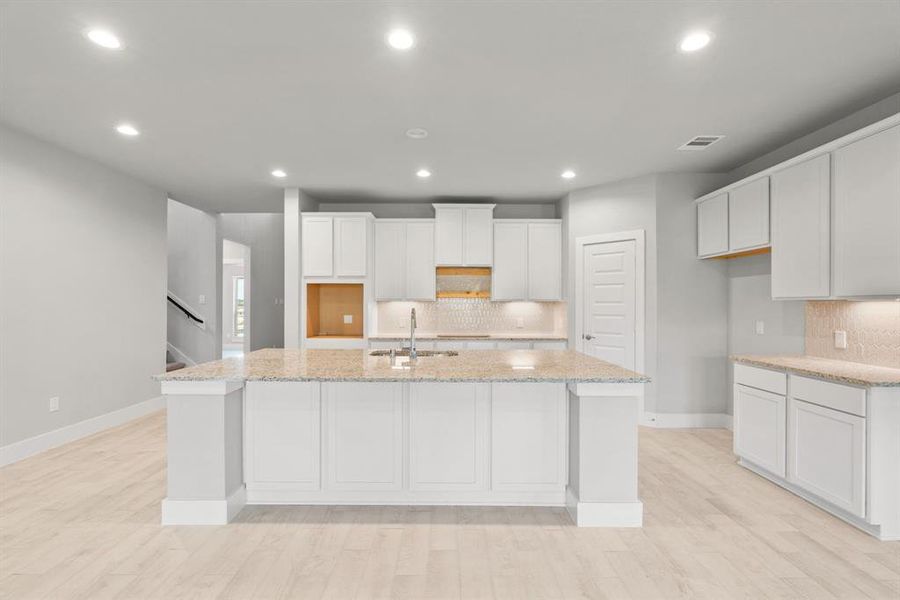 Discover another perspective of this stunning kitchen, massive island, and generously appointed with an abundance of counter space. Sample photo of completed home with similar floor plan. Actual colors and selections may vary.