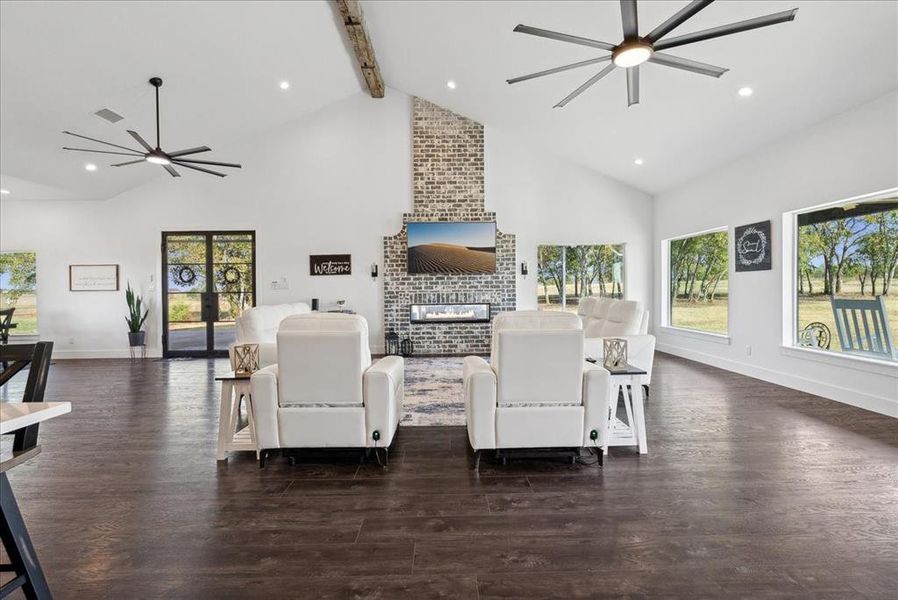 Living room with beam ceiling, a fireplace, high vaulted ceiling, and dark wood-type flooring