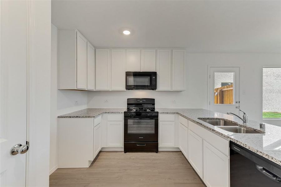 Kitchen featuring light hardwood / wood-style flooring, sink, white cabinetry, and black appliances