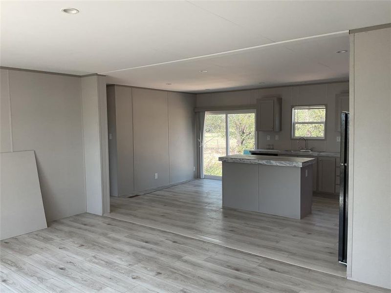 Kitchen with gray cabinetry, light wood-type flooring, a kitchen island, and sink