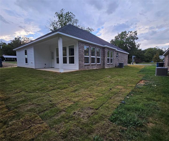 Rear view of property with central air condition unit, a yard, and a patio area