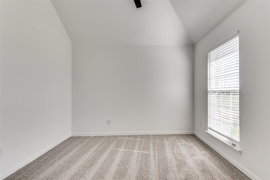 Empty room with vaulted ceiling and light colored carpet