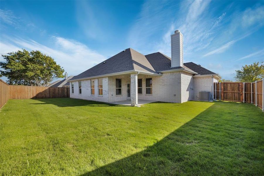 Back of property with a lawn, cooling unit, and a patio area