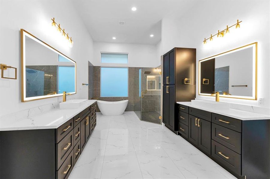 His and hers quartz vanities in the large primary with quartz countertops, warm brass hardware, ceramic vessel sinks and black cabinets. Plenty of storage for linens and toiletries!