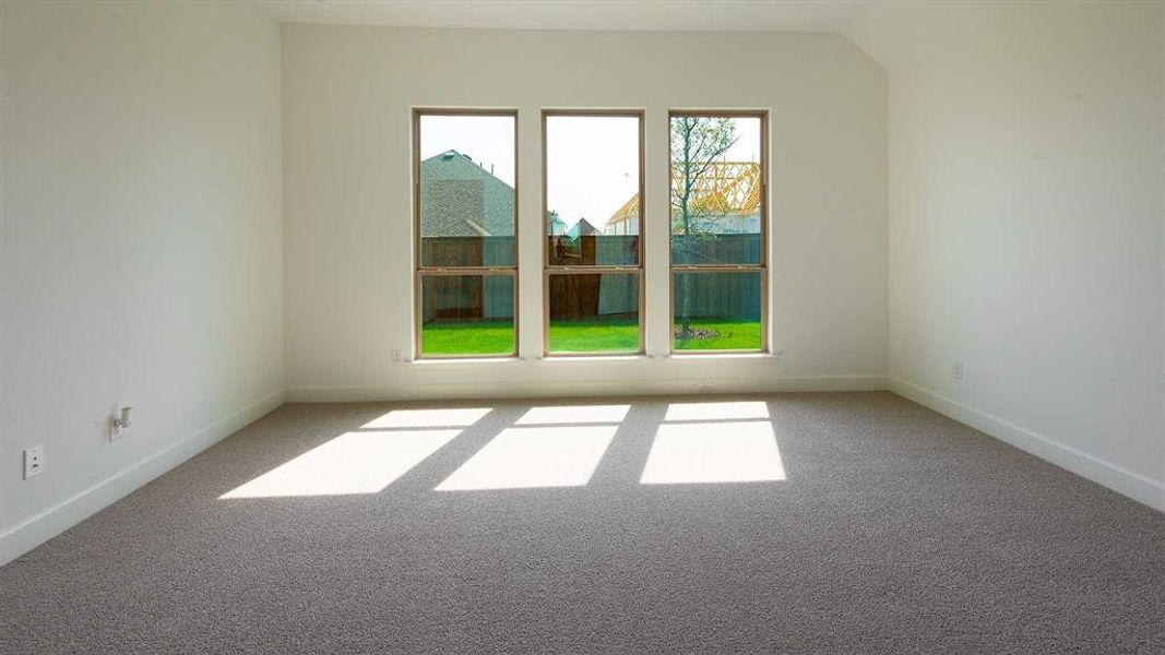 Spare room featuring vaulted ceiling and carpet flooring