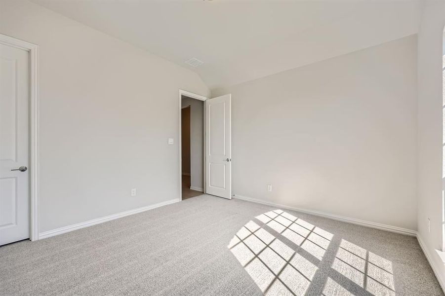 Carpeted spare room with vaulted ceiling