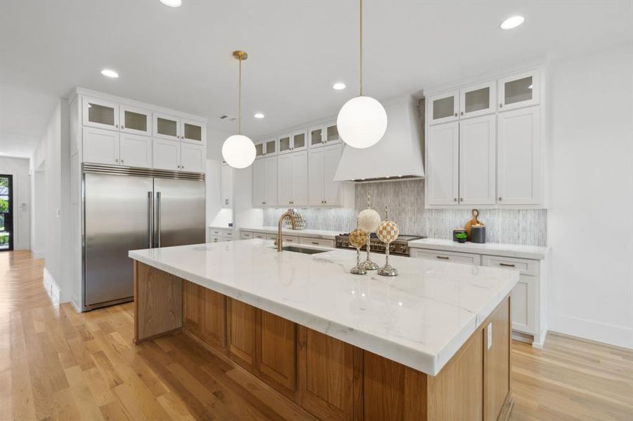 Kitchen featuring a stained center island with sink, custom exhaust hood, stainless steel appliances, and white cabinets