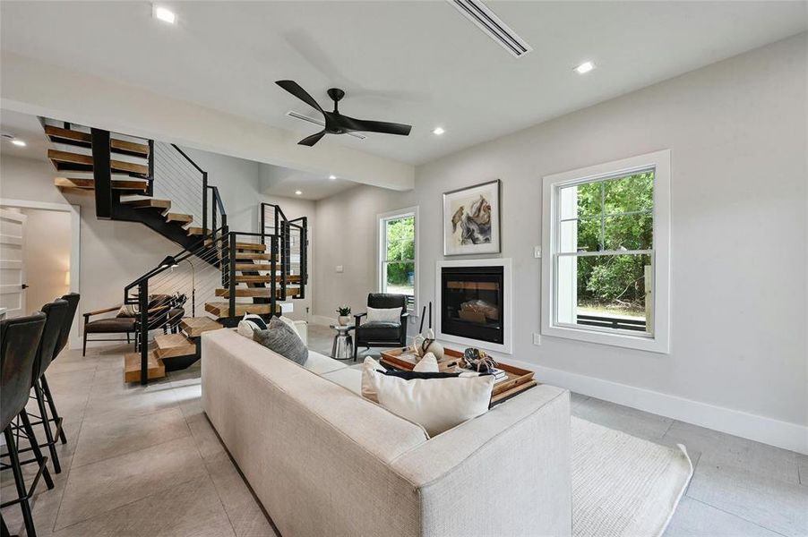 The living area features a cozy fireplace and an open staircase that extends to the upper level, creating a spacious and airy ambiance in this open floor plan.