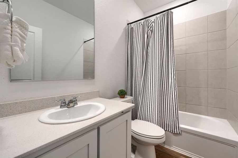 Full bathroom featuring hardwood / wood-style flooring, vanity, toilet, and shower / bath combination with curtain