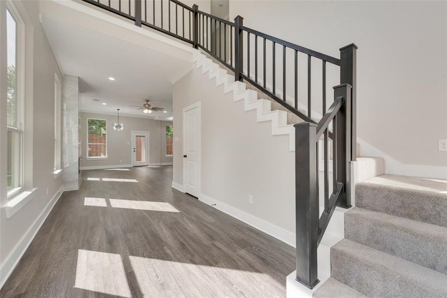 Staircase with dark hardwood / wood-style floors and ceiling fan with notable chandelier