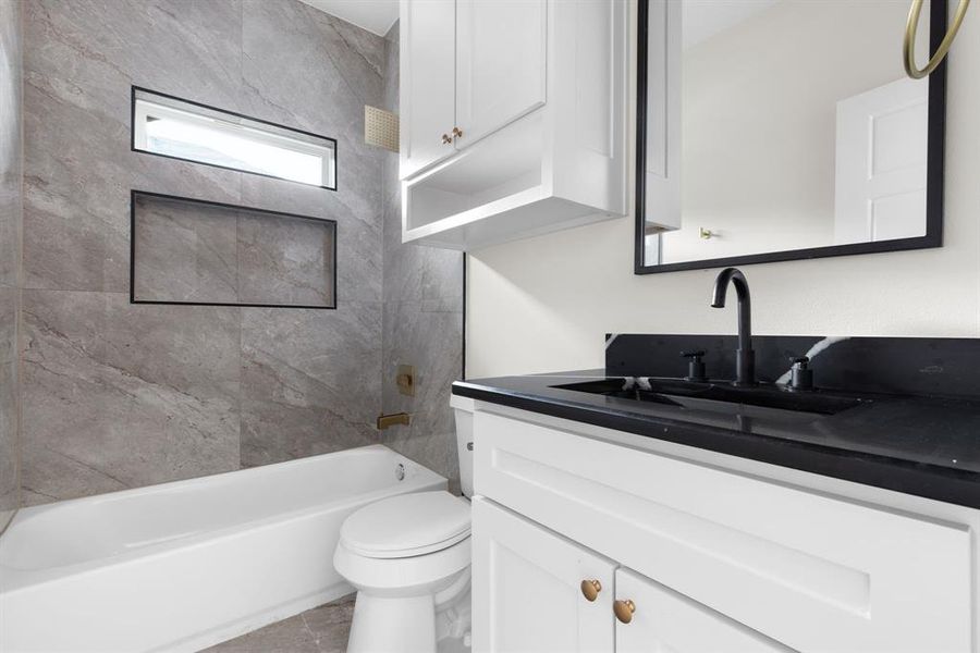 Full bathroom featuring tiled shower / bath combo, vanity, and toilet