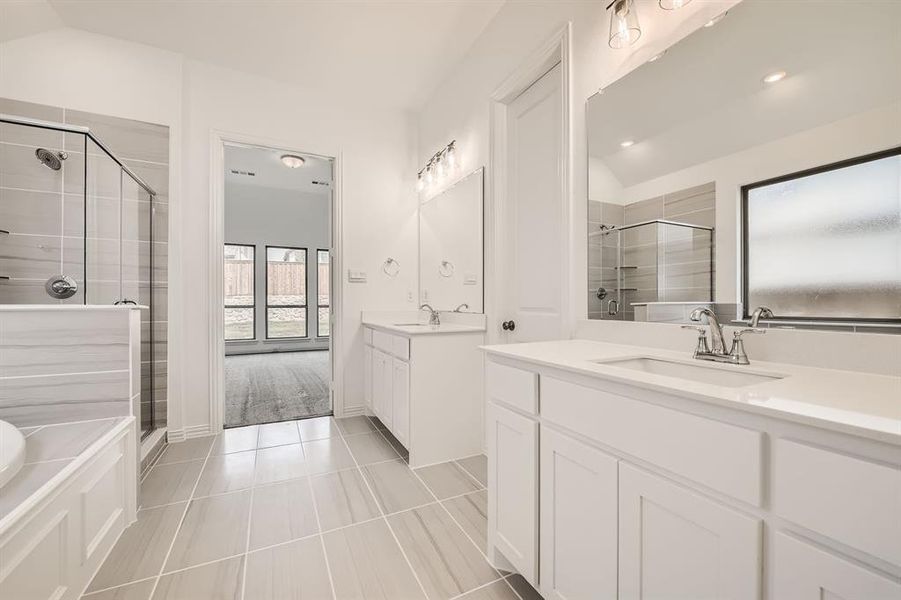 Bathroom featuring independent shower and bath, tile patterned floors, double sink vanity, and vaulted ceiling