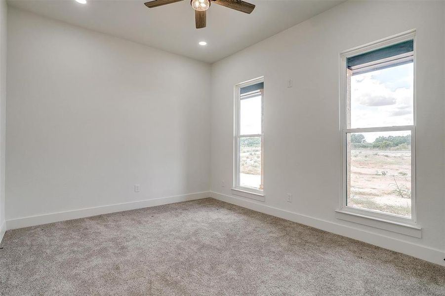 Carpeted room featuring ceiling fan and a wealth of natural light