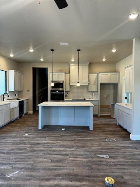 Kitchen featuring pendant lighting, dark wood-type flooring, oven, and a kitchen island