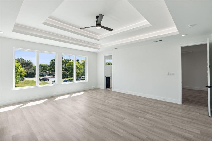 Living room with ceiling fan, light hardwood / wood-style floors, and a raised ceiling