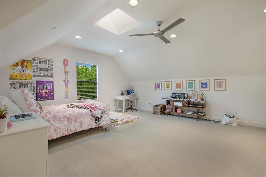 Bedroom with vaulted ceiling with skylight, carpet, and ceiling fan