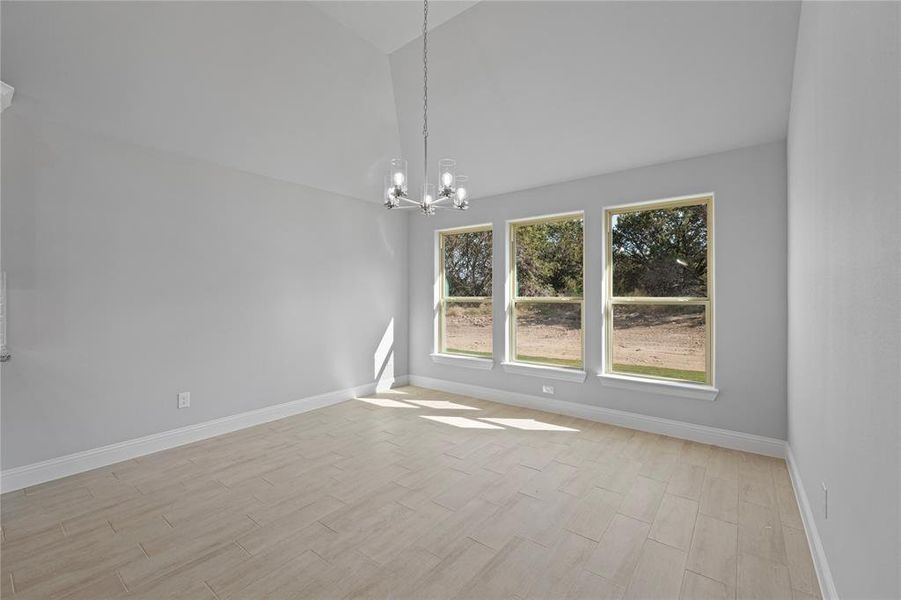 Dining room with a chandelier, light wood-type flooring, and vaulted ceiling