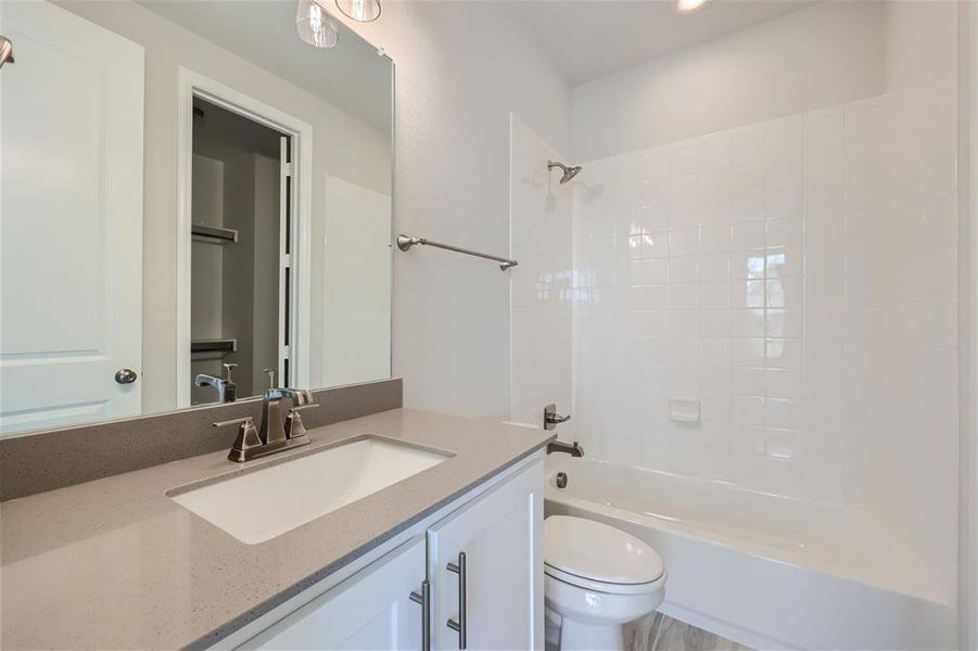 Full bathroom featuring vanity, tiled shower / bath, and toilet