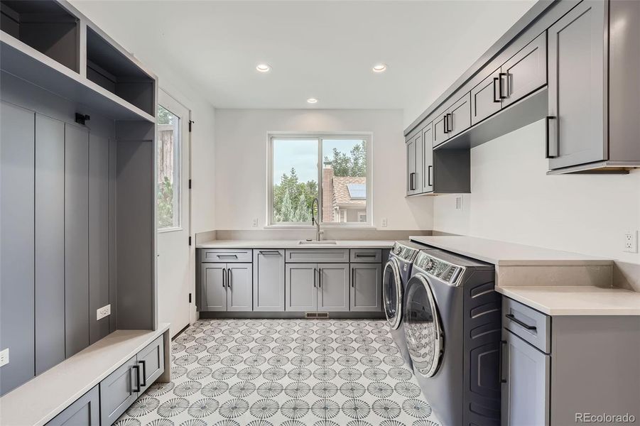 Large mud-laundry room on main level with storage and utility sink.