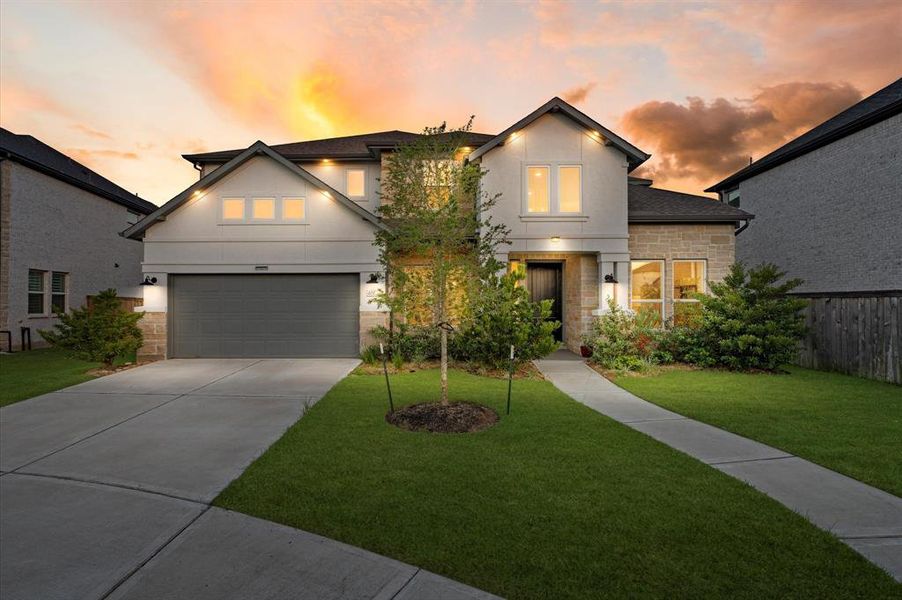 Approaching this Avalon Riverstone home, you're greeted by a meticulously manicured front lawn that exudes curb appeal and welcomes you with its lush greenery.