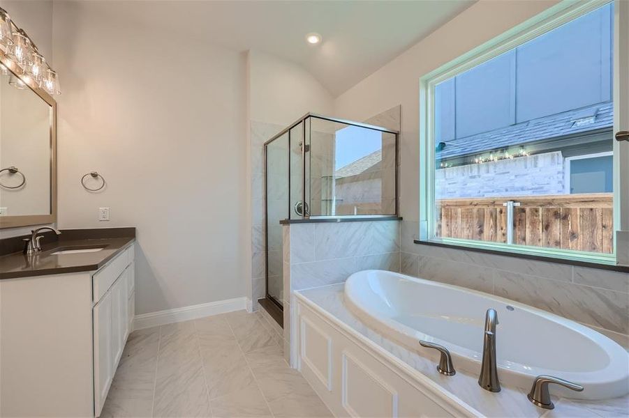 Bathroom featuring tile floors, vanity with extensive cabinet space, lofted ceiling, and plus walk in shower