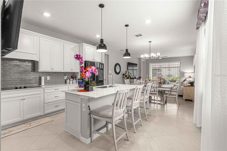 Kitchen has beautiful backsplash, cooktop, and wall mount for tv