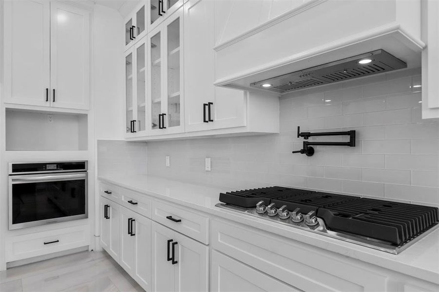 Kitchen with appliances with stainless steel finishes, white cabinets, and decorative backsplash