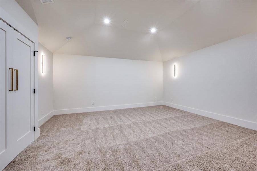 Spare room with light carpet and vaulted ceiling