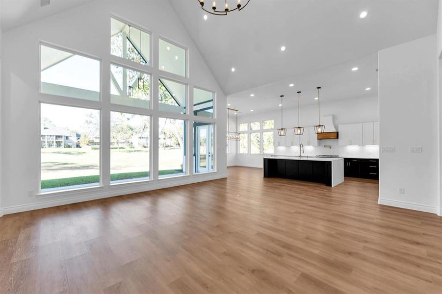 The open living area with kitchen and dining room in the background. The large windows and 21' high ceiling allow for tons of natural light and beautiful golf course views.