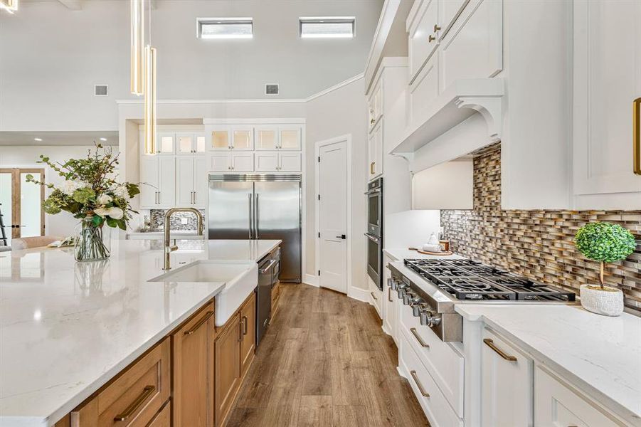 Kitchen with appliances with stainless steel finishes, light hardwood / wood-style flooring, sink, decorative backsplash, and white cabinetry