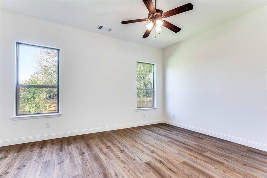 Spare room featuring plenty of natural light, ceiling fan, and light hardwood / wood-style flooring