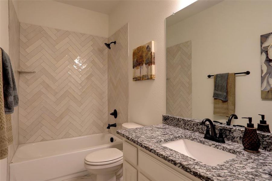 Full bathroom featuring tiled shower / bath, vanity with extensive cabinet space, and toilet