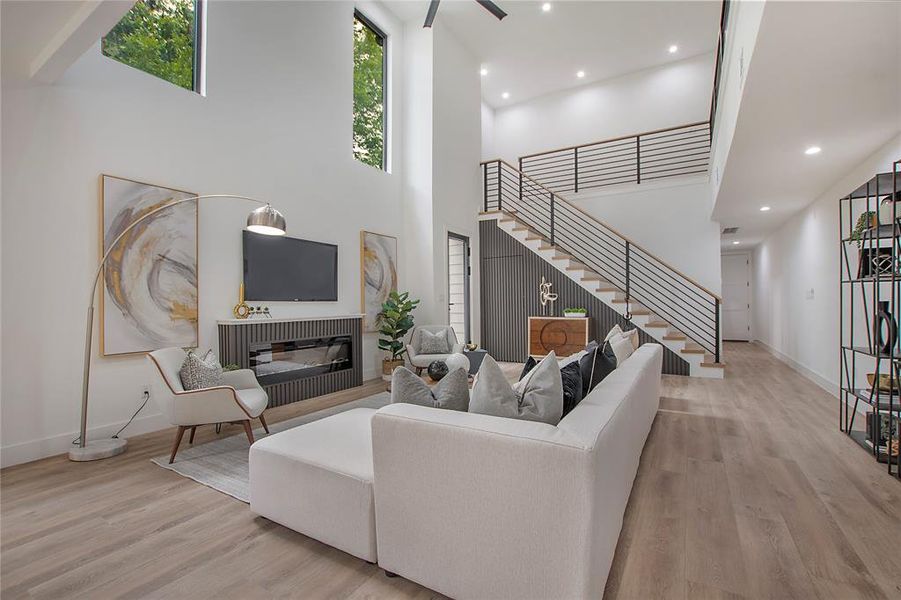 Living room featuring a high ceiling, light wood-type flooring, and ceiling fan