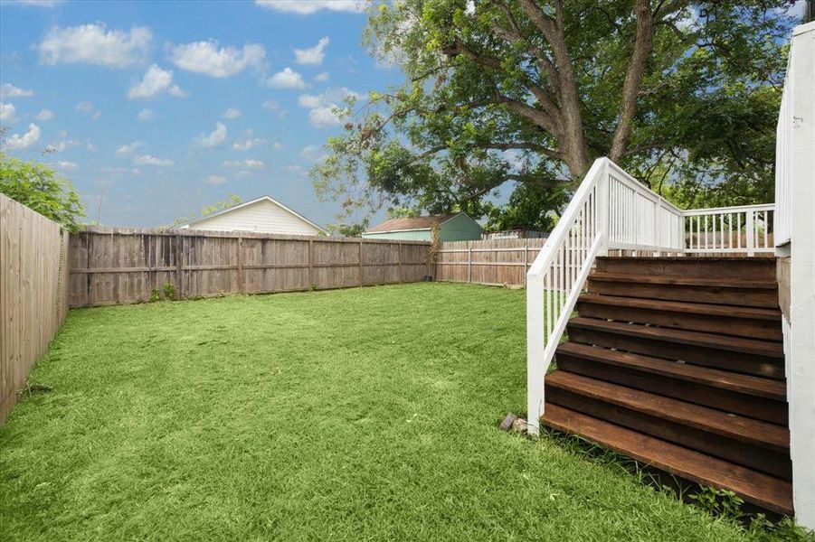 The back porch overlooks a sprawling fenced yard with plenty of room for outdoor play.
