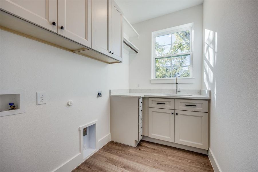 Laundry area featuring sink, cabinets, hookup for an electric dryer, hookup for a washing machine, and light hardwood / wood-style floors