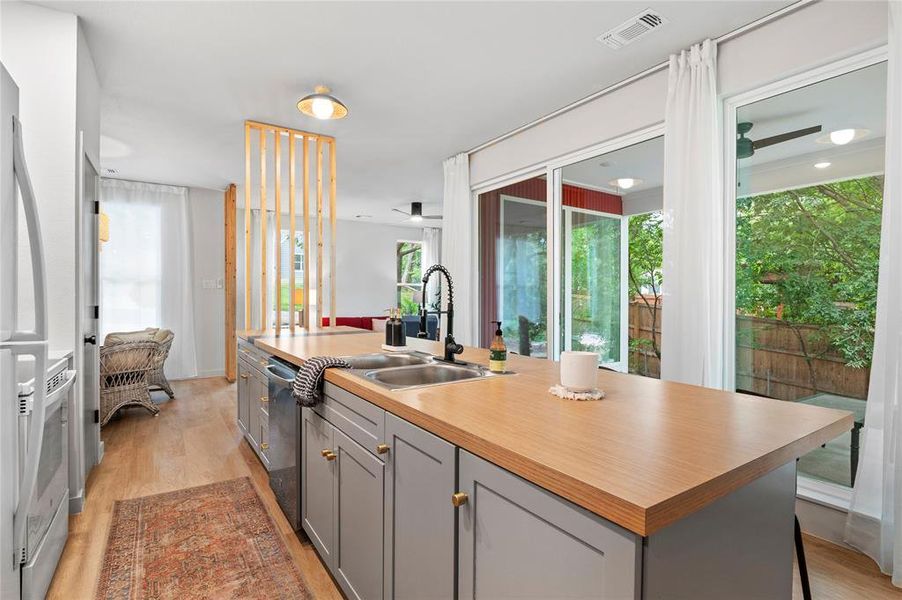 Kitchen with light hardwood / wood-style floors, a center island with sink, and gray cabinetry