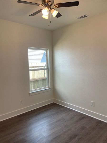 Spare room featuring dark wood-type flooring and ceiling fan