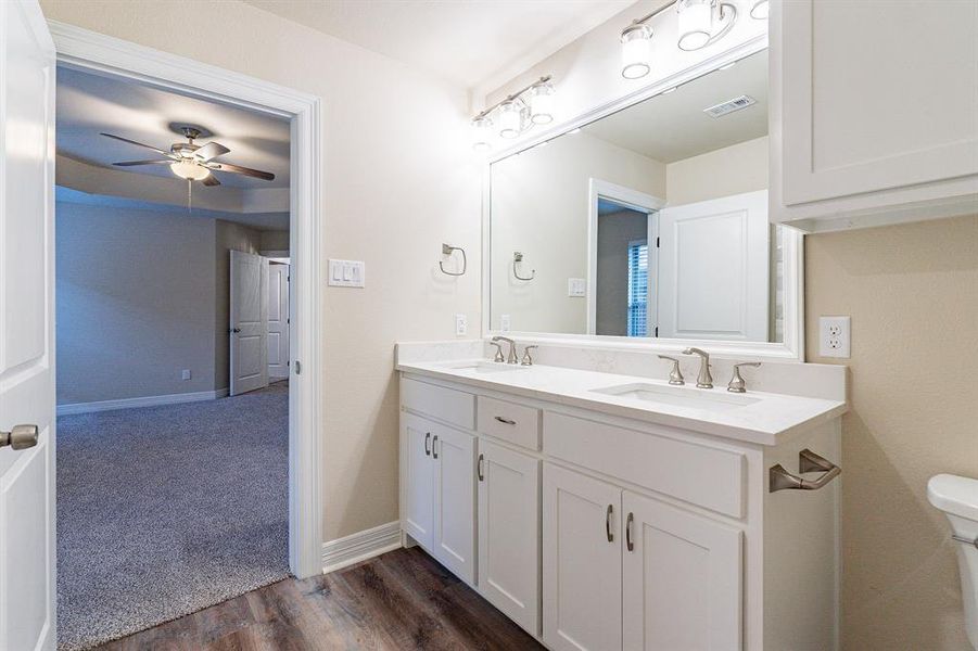 Bathroom with hardwood / wood-style flooring, ceiling fan, double vanity, decorative lighting